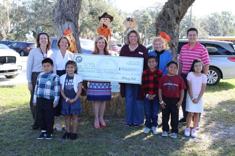 Representative Melony Bell presents a $350,000 check to RCMA Mulberry Community Academy staff and students, celebrating funding for a water treatment system.